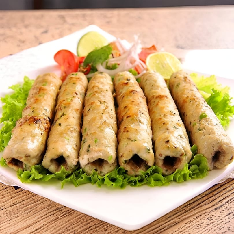Six chicken seekh kebabs from Masala Express, garnished with lettuce, lime, tomatoes, and onions.