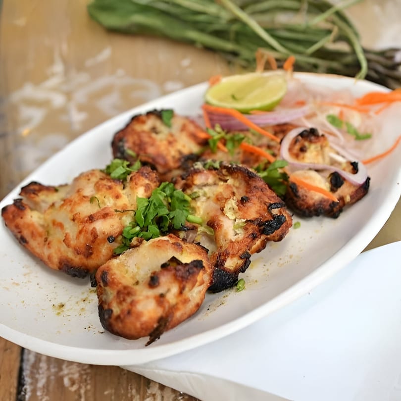 Masala Express's Indian chicken tikka, garnished with cilantro, lime, and sliced onions.